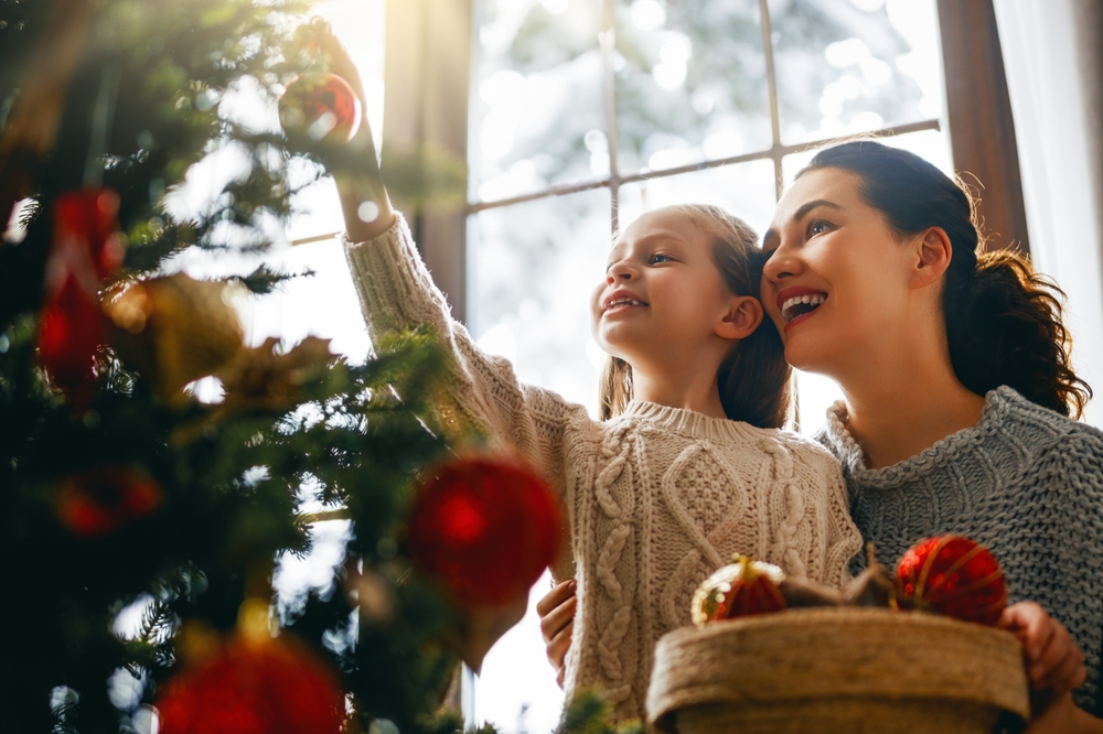 parent and kid decorating christmas tree