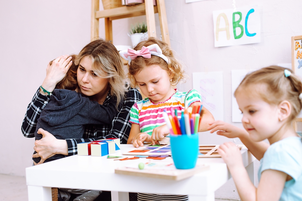 YoungEducatorEmbraceAndCalmDownCryingBoyInKindergarten Educator comforting an overwhelmed preschooler in a classroom